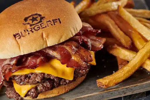 BurgerFi bacon burger and fries served on a wooden plate. 