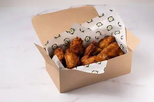 A box of BurgerFi chicken wings placed on a white marble top. 