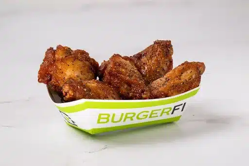 Crispy chicken wings from BurgerFi placed on a marble top. 