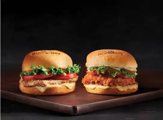  Two burgers from BurgerFi on a wooden table. 